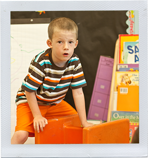 Photograph: A preschool-aged boy stacks plastic chairs in a classroom. (Photograph by Alex Lazara)