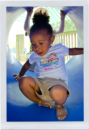 Photograph: A preschool-aged girl shoots through the tube of a playground slide. (Photograph by Alex Lazara)