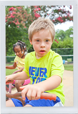 Photograph: A preschool-aged boy looks over the handlebars of his tricycle. (Photograph by Alex Lazara)