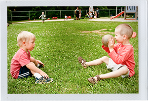 Photograph: Two preschool-aged children on a grassy space playing with a ball
