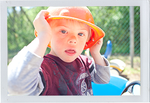 Photograph: A child adjusts a toy helmet while sitting in a plastic playground car (Photograph by Alex Lazara)