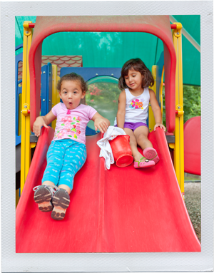 Photograph: Two preschool aged girls slide down a playground slide together. (Photograph by Alex Lazara)