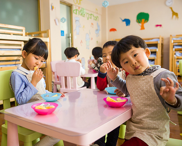 Photograph: A group of children are gathered around a table in a preschool class.